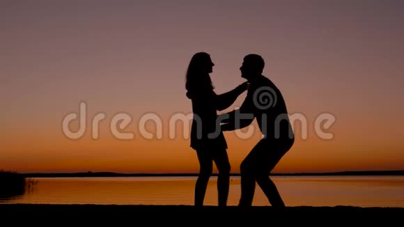 一对相爱的男女在夕阳下亲吻拥抱的剪影视频的预览图