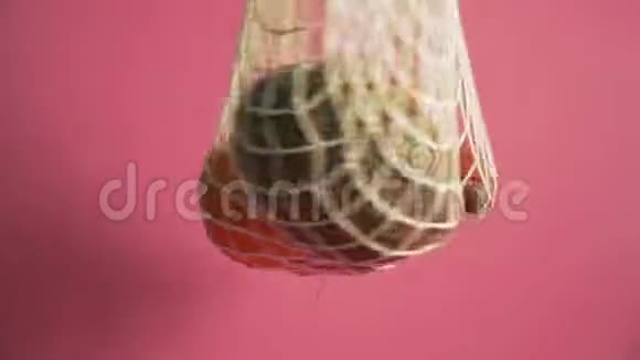 水果和蔬菜在网袋替代塑料购物袋在粉红色背景4k视频的预览图
