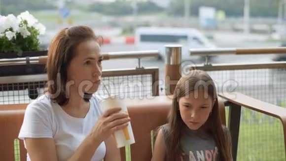 可爱的女人和一个10岁的女儿在露台上的咖啡馆里一位美女正在喝一杯鸡尾酒视频的预览图