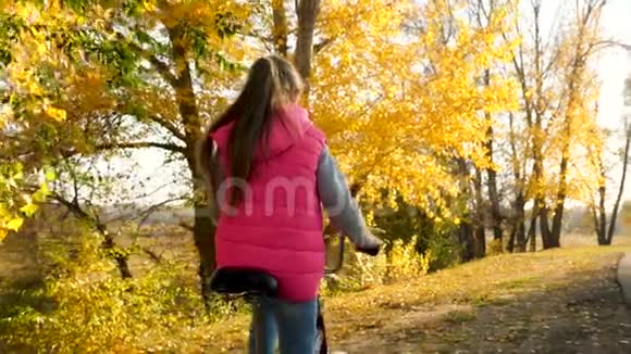 女孩的手拿着弯曲的自行车把手女孩骑自行车在秋天的公园里微笑特写视频的预览图