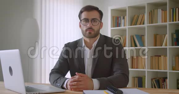 戴眼镜的成年白种人英俊商人用笔记本电脑在办公室里看相机的特写肖像视频的预览图