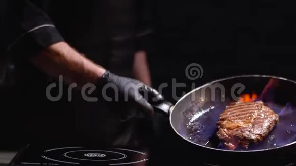 男性手戴黑色橡胶手套手拿煎锅和烤牛排厨师把锅烧开了视频的预览图