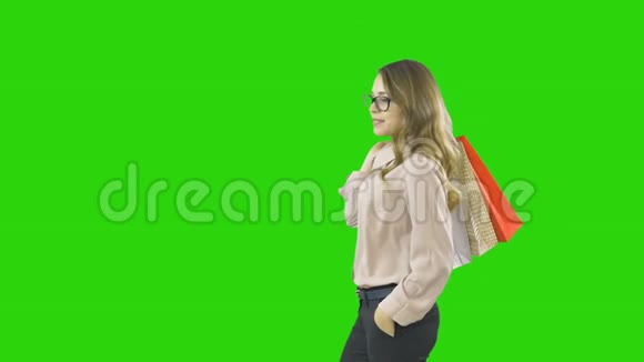 手里拿着购物袋的女人在绿色的屏幕上微笑视频的预览图