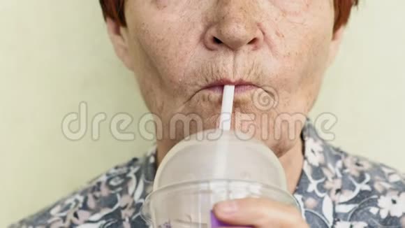 一位老妇人喝着一杯稻草特写的饮料视频的预览图