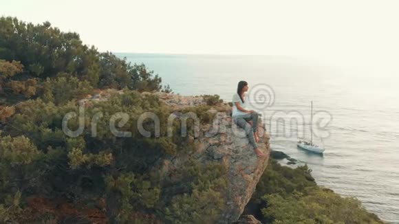 女人坐在巨石上看海景视频的预览图