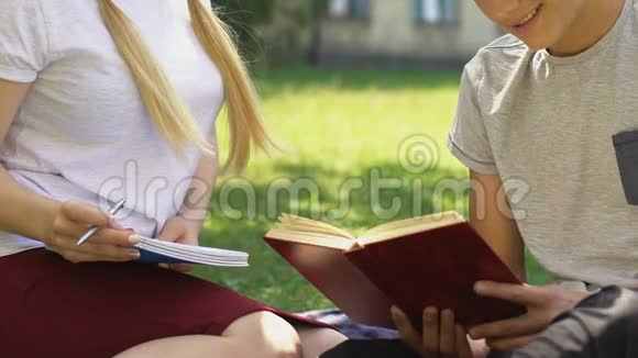 聪明的十几岁男孩帮助女孩在户外做作业准备考试视频的预览图