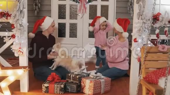 家人为圣诞节打包礼物带圣诞装饰的家庭在门廊微笑视频的预览图