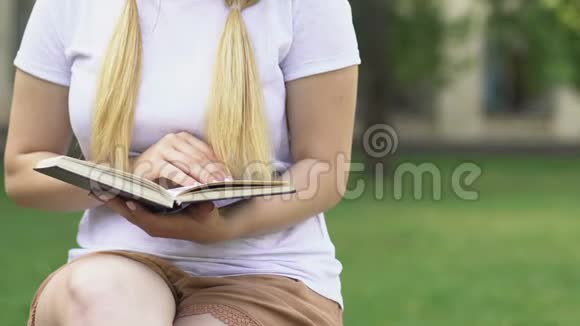 金发女孩在户外看书学生准备考试修改信息视频的预览图