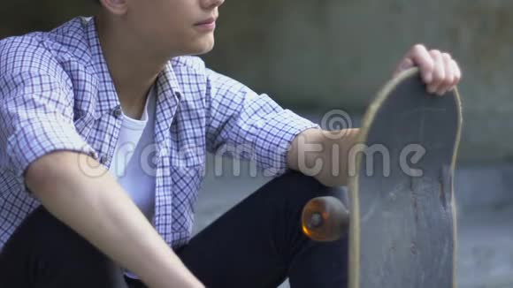 青少年男孩孤独地坐在滑板上无聊地没有朋友局外人视频的预览图