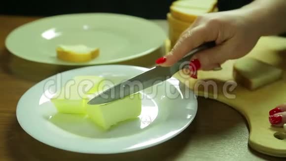 一个女人切一片黄油把黄油涂在罐装面包上视频的预览图