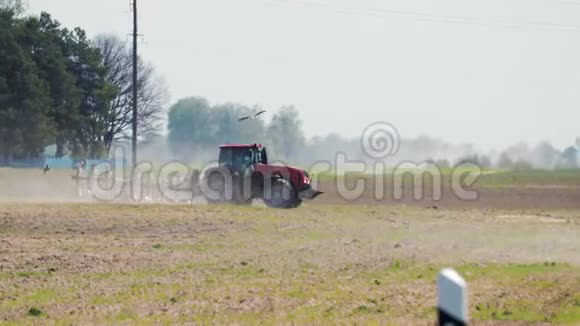 红拖拉机在炎热干燥的天气下在电线杆的背景下耕种土壤视频的预览图