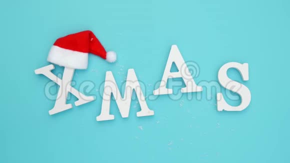 圣诞节从卷白色字母红色圣诞老人帽子和降雪蓝色背景概念圣诞快乐顶级视频的预览图