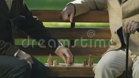 两个退休老人在公园长椅上下棋游戏策略大脑锻炼爱好视频的预览图