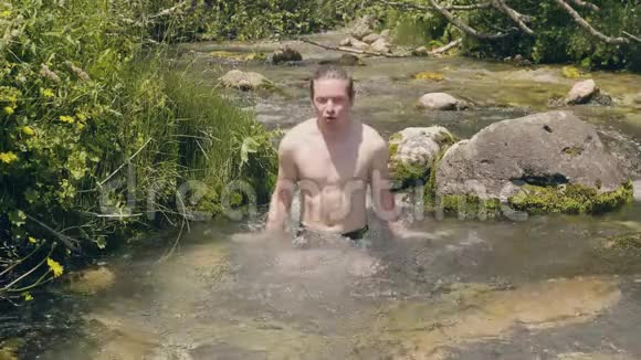 快乐的人蘸着山泉水溅起水花在河里洗澡的人视频的预览图