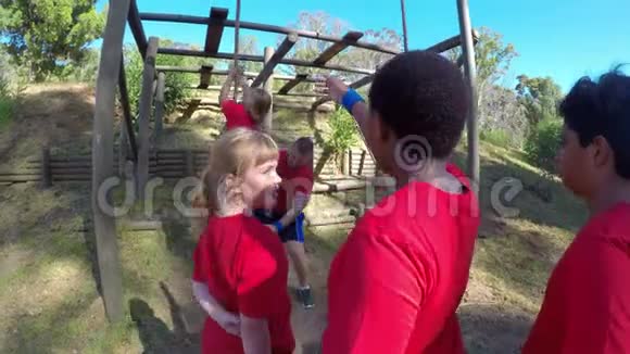 协助一名女生在4k障碍课程中爬绳的教练视频的预览图
