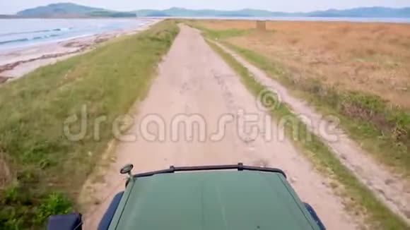 车罩的视图汽车沿着一条尘土飞扬的道路行驶在绿色的草地上视频的预览图