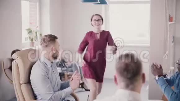 快乐的白种人女老板跳胜利舞给多民族的办公室同事五次机会笑得慢视频的预览图