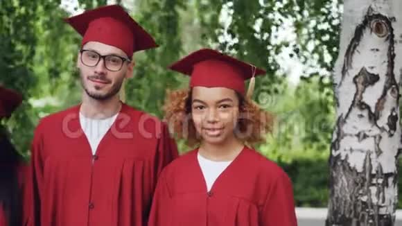 穿着红色毕业礼服和灰泥板站在一起的跨国毕业生群体的肖像视频的预览图