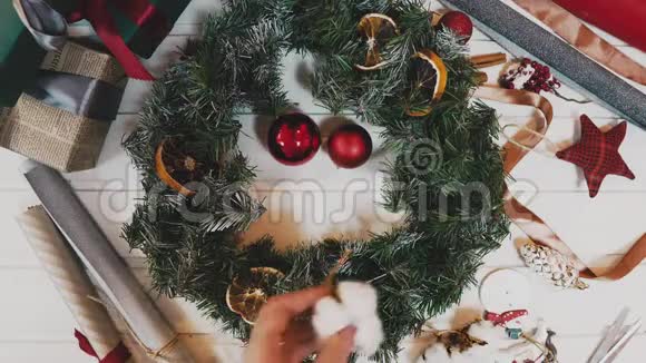 花店手在木制桌面上制作圣诞花环的俯视图视频的预览图