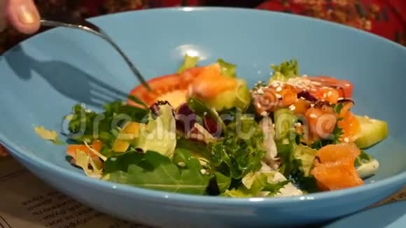 新鲜混合沙拉与绿叶蔬菜和蔬菜在蓝色陶瓷碗吃在餐厅与金属叉子视频的预览图