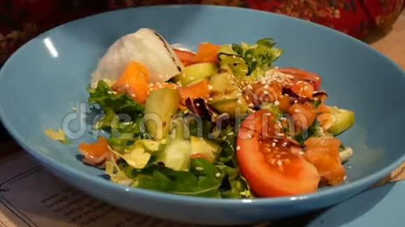 新鲜混合沙拉与绿叶蔬菜和蔬菜在蓝色陶瓷碗吃在餐厅与金属叉子视频的预览图