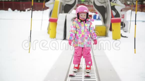 冬季户外运动中的小女孩呆在滑雪传送带上孩子开始滑雪了度假村快乐滑雪体验视频的预览图