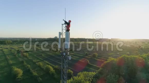 在蜂窝天线上工作的快乐男人无线电信塔上的技术人员举起大拇指视频的预览图