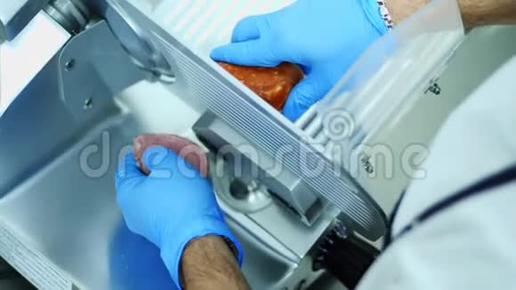 特写食堂工作人员在一个特殊的设备上切割香肠一台切割香肠和奶酪产品的机器视频的预览图