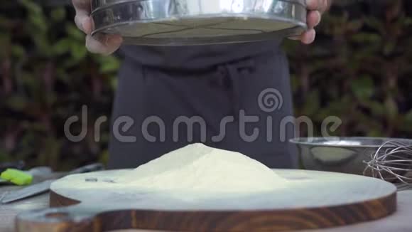 厨师通过筛子筛面粉以烘焙慢动作男性手通过筛子在木板上倒面粉视频的预览图