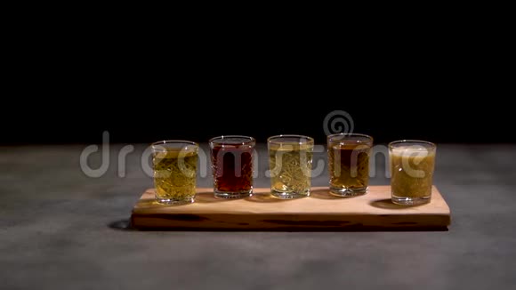 关闭五个不同的酒精镜头在小眼镜站在桌子上孤立的黑色背景视频的预览图