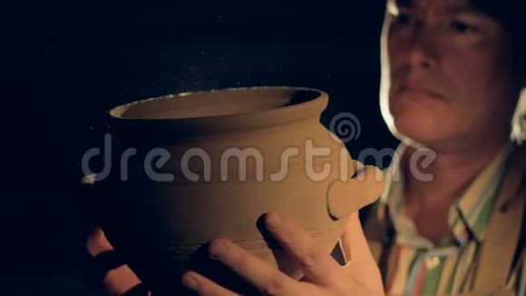 陶器工人看着一个手工制作的罐子视频的预览图