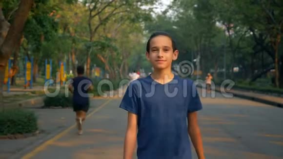 一个少年在一个大公园里愉快地走在大自然中的肖像视频的预览图