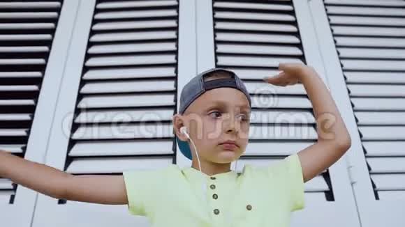 一个白人小男孩正在听音乐用手做手势跳舞一个跳舞的有趣男孩的画像视频的预览图