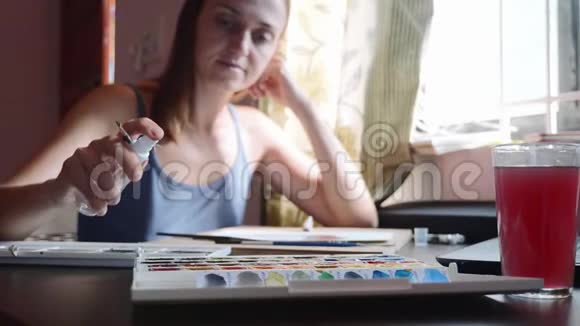一个年轻的女人在用水彩画之前会滋润颜料视频的预览图