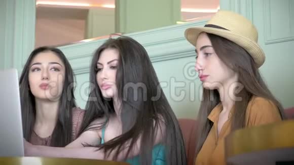 女朋友坐在自助餐厅讨论项目三个女朋友一起谈论坐在沙发上的时装设计视频的预览图
