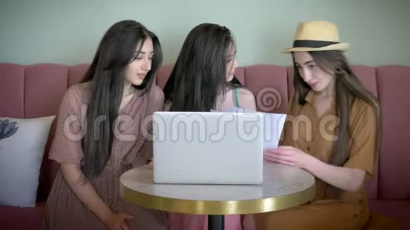 三个活跃的女朋友在网上商店里看宣传海报选择新衣服笑着在网上玩视频的预览图