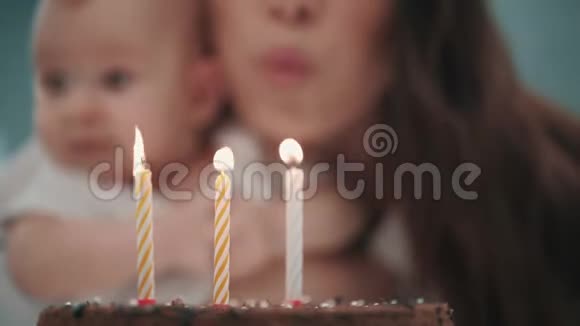 带着婴儿在生日蛋糕上吹蜡烛的女人家庭生日聚会视频的预览图