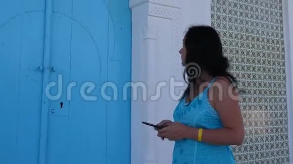 有电话的女人在蓝色阿拉伯门附近等人视频的预览图