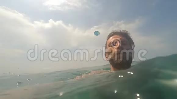 大胡子男在阳光明媚的日子里在海水中游泳背景是夏天视频的预览图