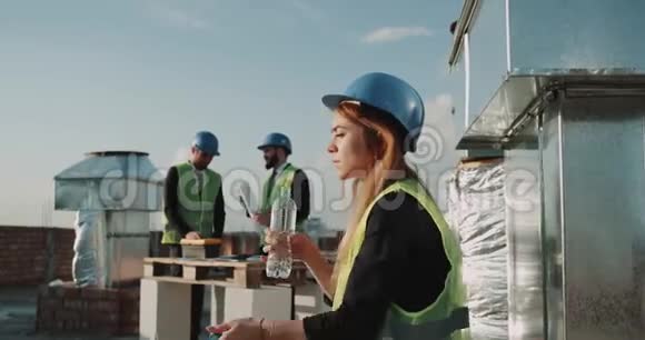 在炎热的工作日建筑工地的年轻女工有少量的饮水背景建筑工人有视频的预览图