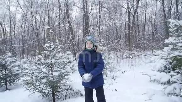 少年男孩在冬天的森林里扔雪积极的生活方式冬季活动户外冬季游戏的概念视频的预览图