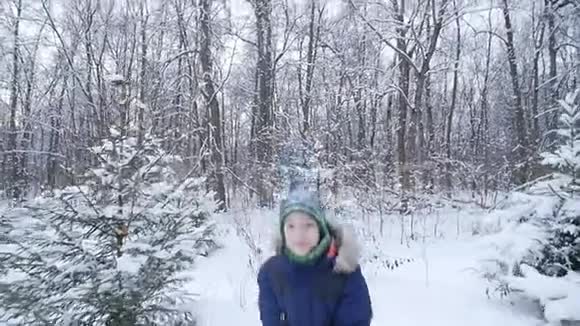 少年男孩在冬天的森林里扔雪积极的生活方式冬季活动户外冬季游戏的概念视频的预览图