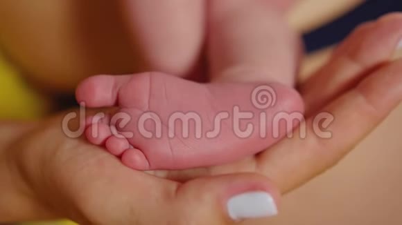 宝宝的脚在妈妈手里微小的新生婴儿的脚在女性心形的手特写妈妈和她的孩子快乐视频的预览图