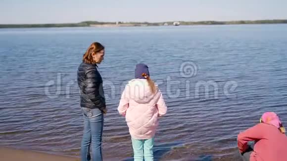 一位年迈的妇女带着一个成年的女儿和孙女沿着海岸散步在一个人身上愉快地交谈和大笑视频的预览图
