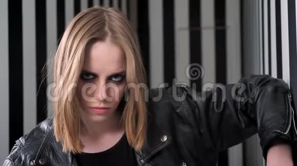 年轻漂亮的女人穿着黑色夹克看着镜头自信有条纹的墙背景视频的预览图