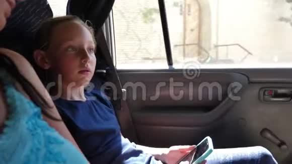 女孩拿着电话和妈妈聊天在热车里旅行视频的预览图