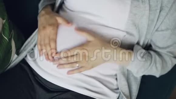 孕妇腹部和柔嫩的女性手的特写用温柔和细心抚摸和抚摸婴儿肿块然后制作视频的预览图