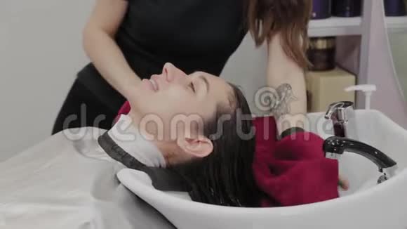 美容美发沙龙一个理发师正在用毛巾把客户的头发洗了之后在水槽里擦拭视频的预览图