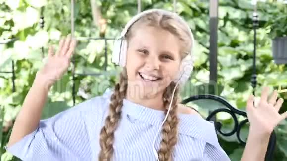 可爱的女孩戴着白色耳机微笑着充满感情地打手势4k视频的预览图