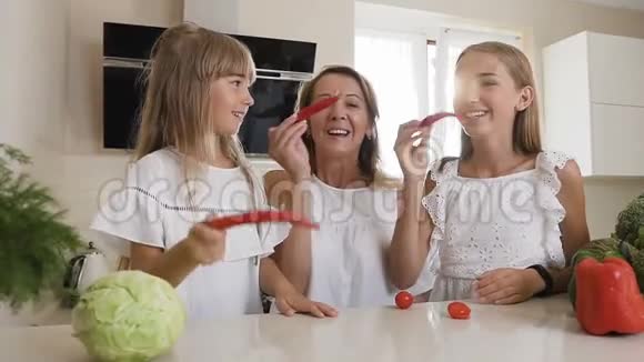 特写镜头漂亮的妈妈和她的两个女儿用红辣椒做胡子开心地笑着摆姿势视频的预览图